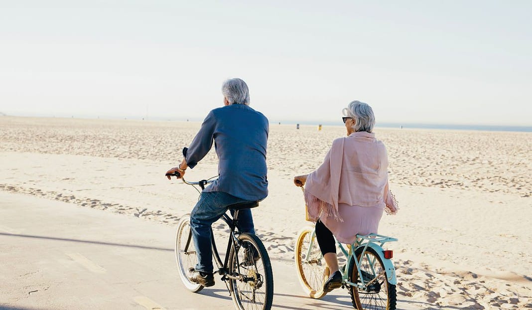 older adults riding bikes on the beach